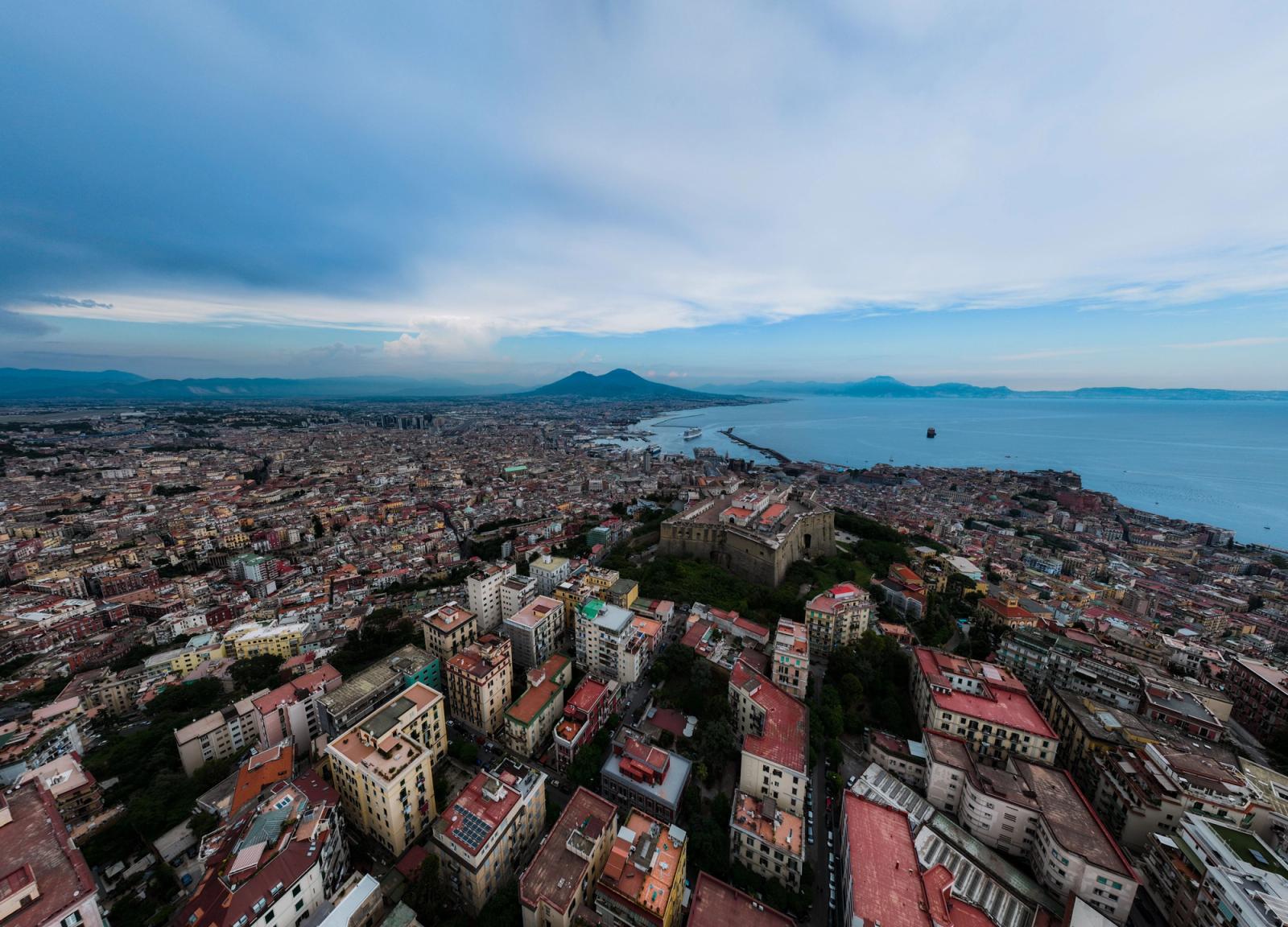 Panoramic aerial view of Naples, Italy, featuring Mount Vesuvius and the Mediterranean Sea