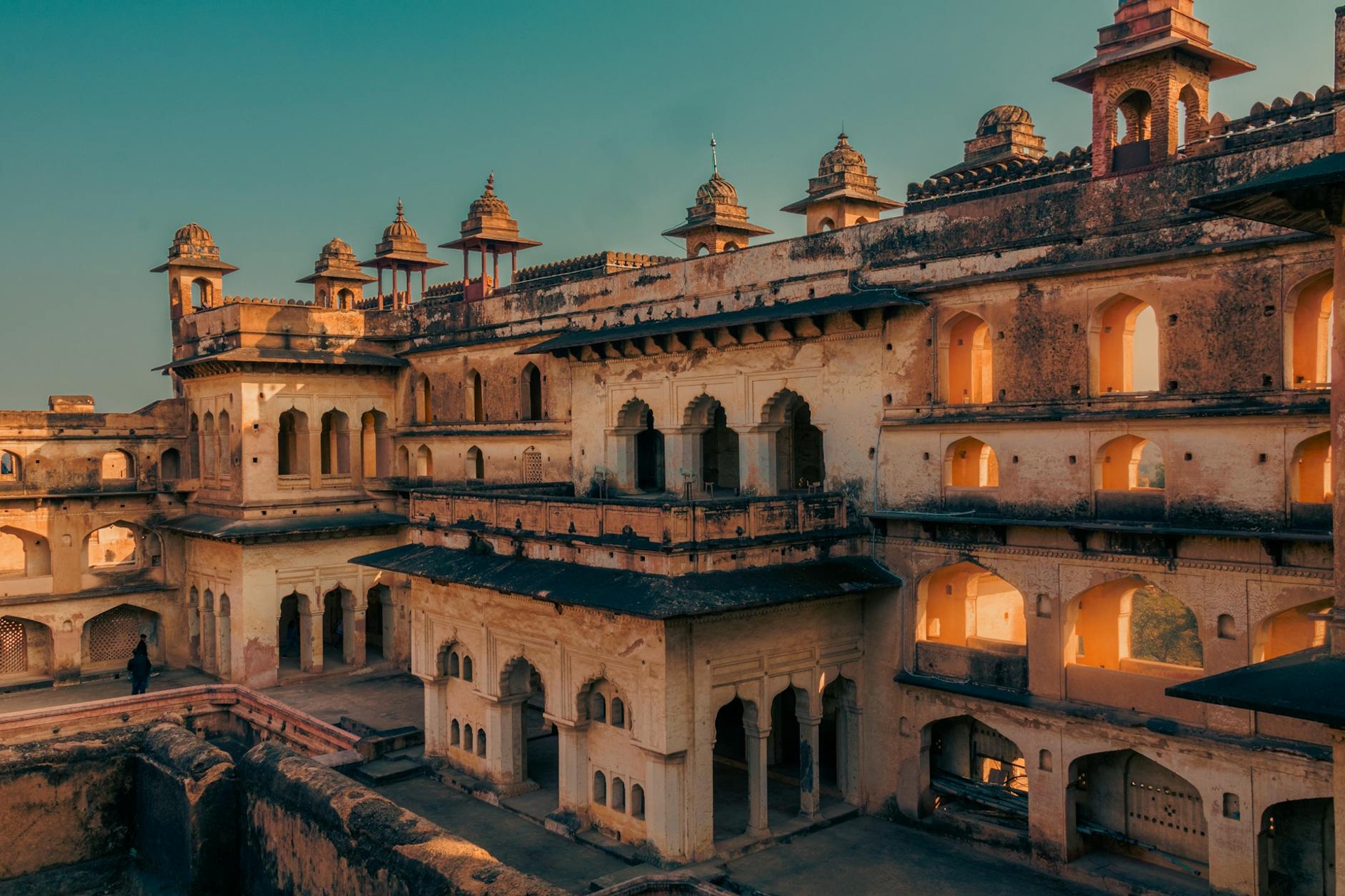 A tiered sandstone fort palace with domed turrets glowing at dusk