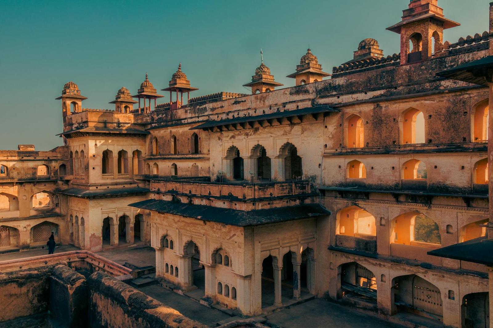 A tiered sandstone fort palace with domed turrets glowing at dusk
