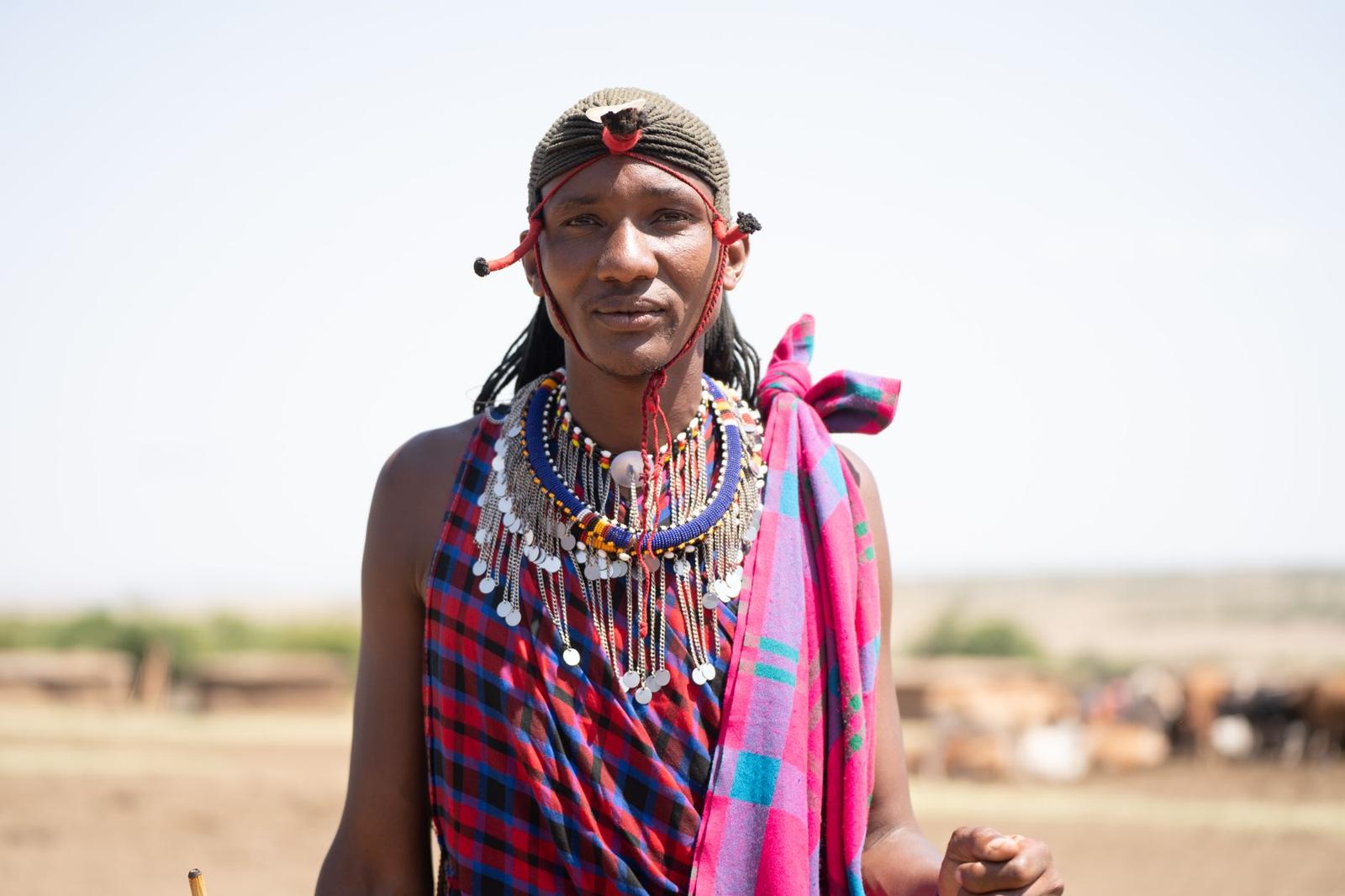 A close-up of a Maasai man wearing a beaded necklace and headdress