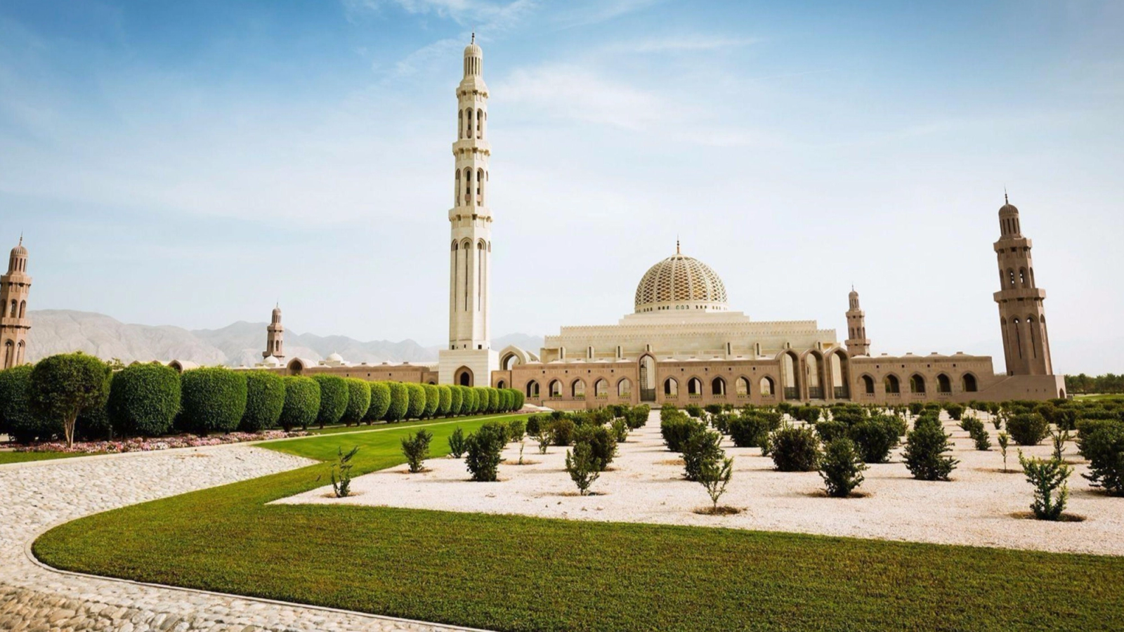 A domed mosque with tall minarets set behind manicured lawns