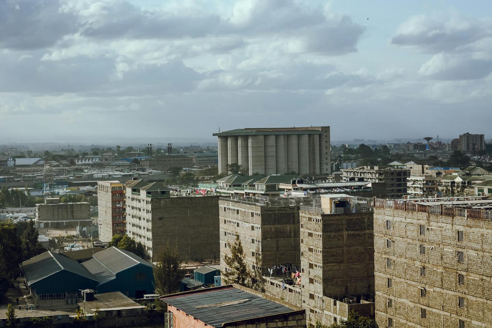 An aerial view of apartment blocks and a cylindrical tower under grey skies