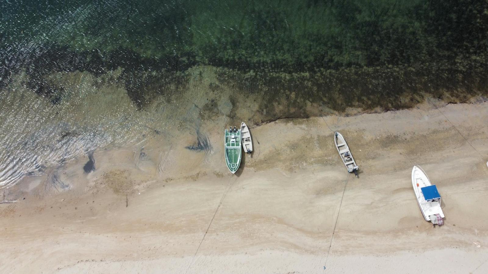 Aerial view of small fishing boats beached on a turquoise shoreline