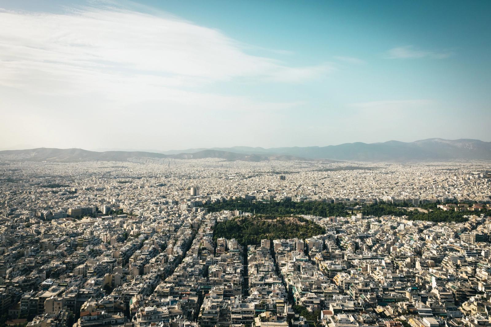 Aerial view of Athens cityscape showcasing urban density with mountains in the background