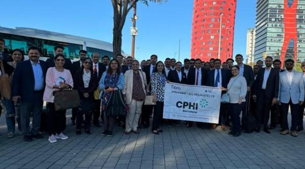 A large group of professionals holding a banner at CPHI event.