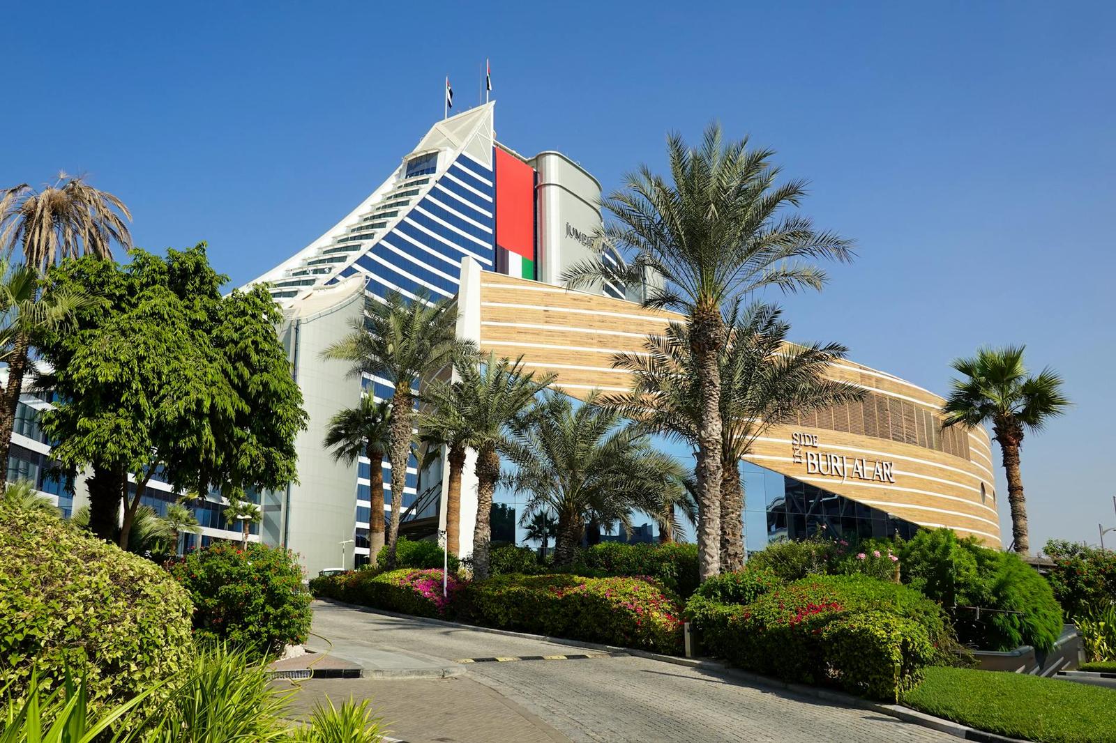 Explore the vibrant Jumeirah architecture with lush palm trees under a clear Dubai sky