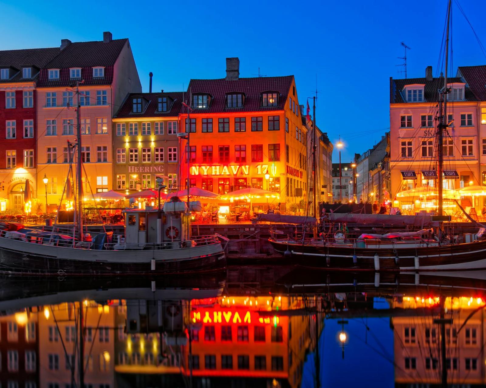 Nyhavn's vibrant waterfront and boats reflected at dusk in Copenhagen, Denmark