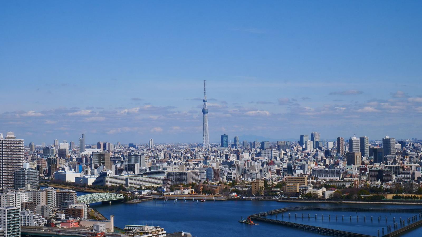 Tokyo Skytree rising above a riverside city skyline under a clear sky