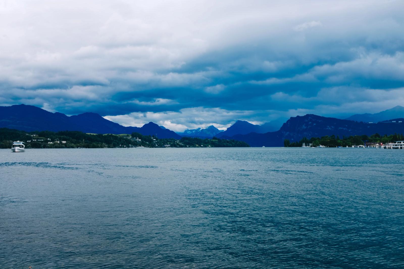 A tranquil lake with distant mountains and dramatic overcast skies, capturing nature's beauty