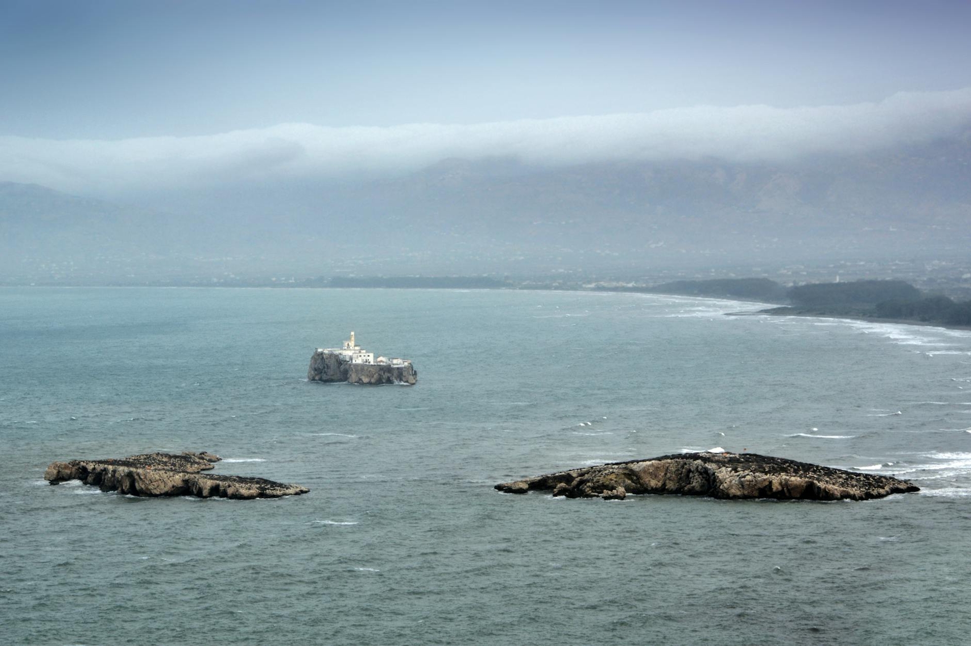 Rocky islets in a misty sea with a coastline fading into fog