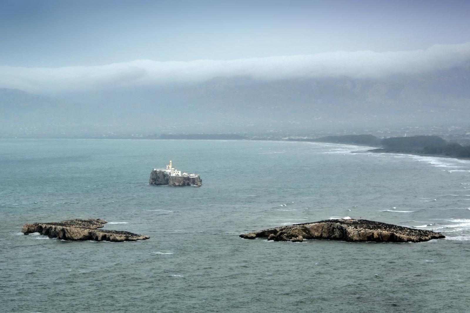 Rocky islets in a misty sea with a coastline fading into fog