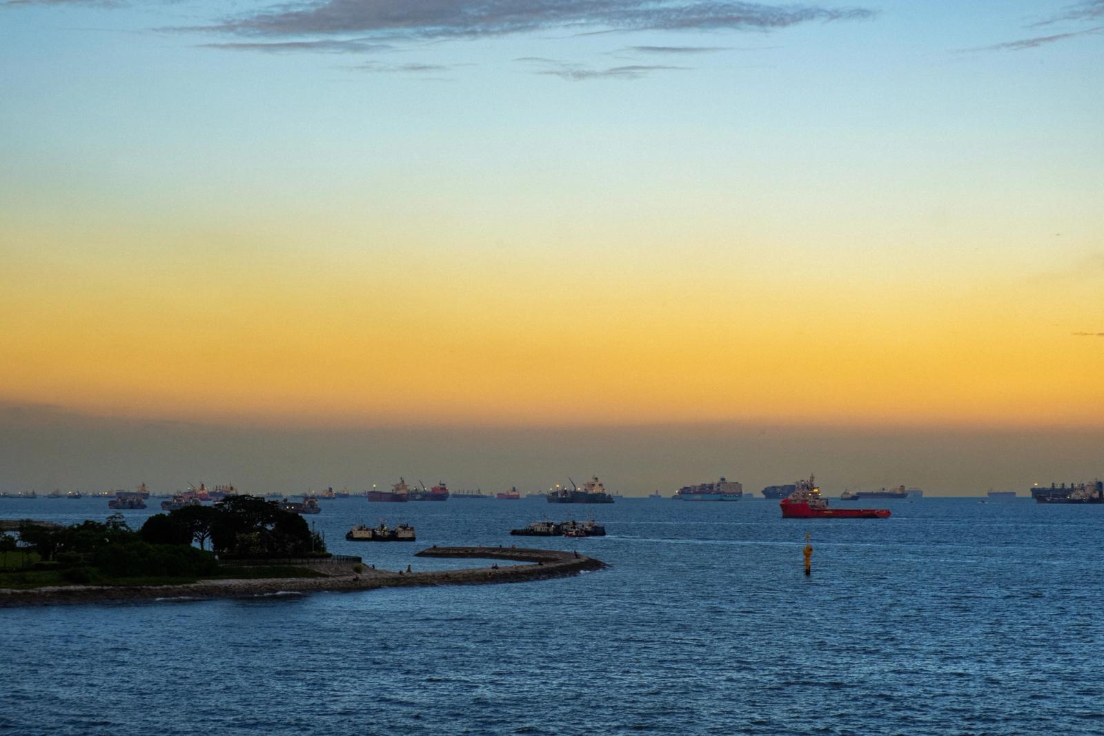 A tranquil sunset view over Singapore's harbor with ships under a vivid sky
