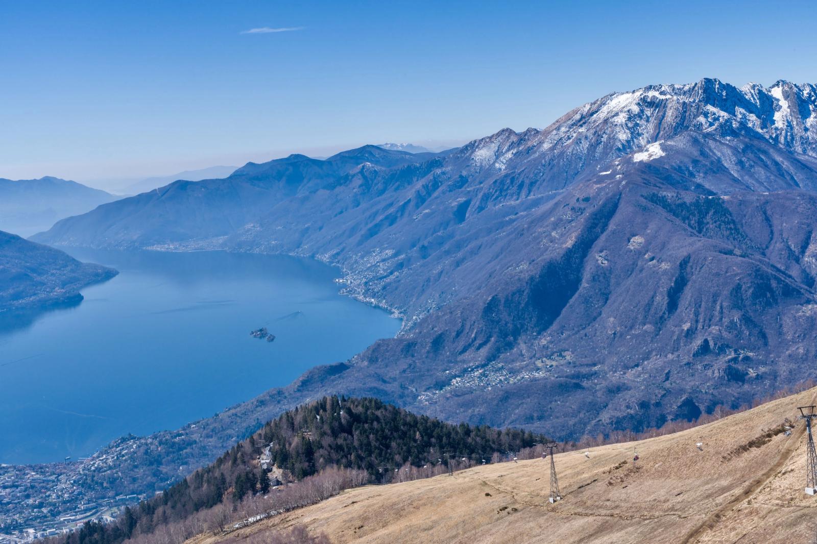 A mountain lake seen from a high ridge with snow-capped peaks beyond