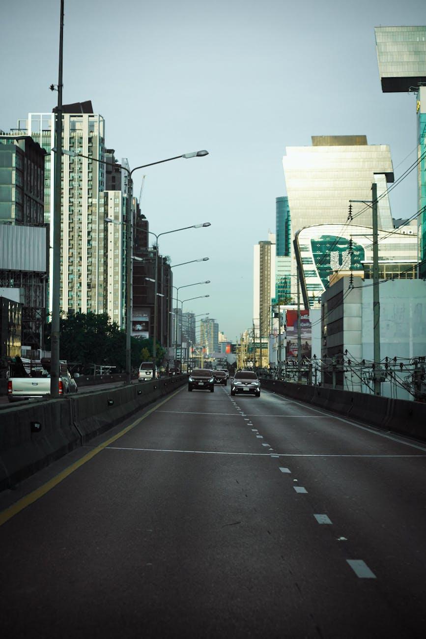 Cars on a wide sunken highway between glass office towers
