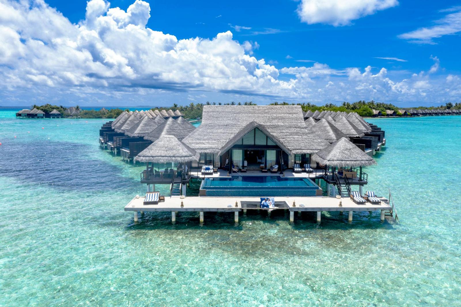 An aerial view of a thatched overwater villa with its own private pool