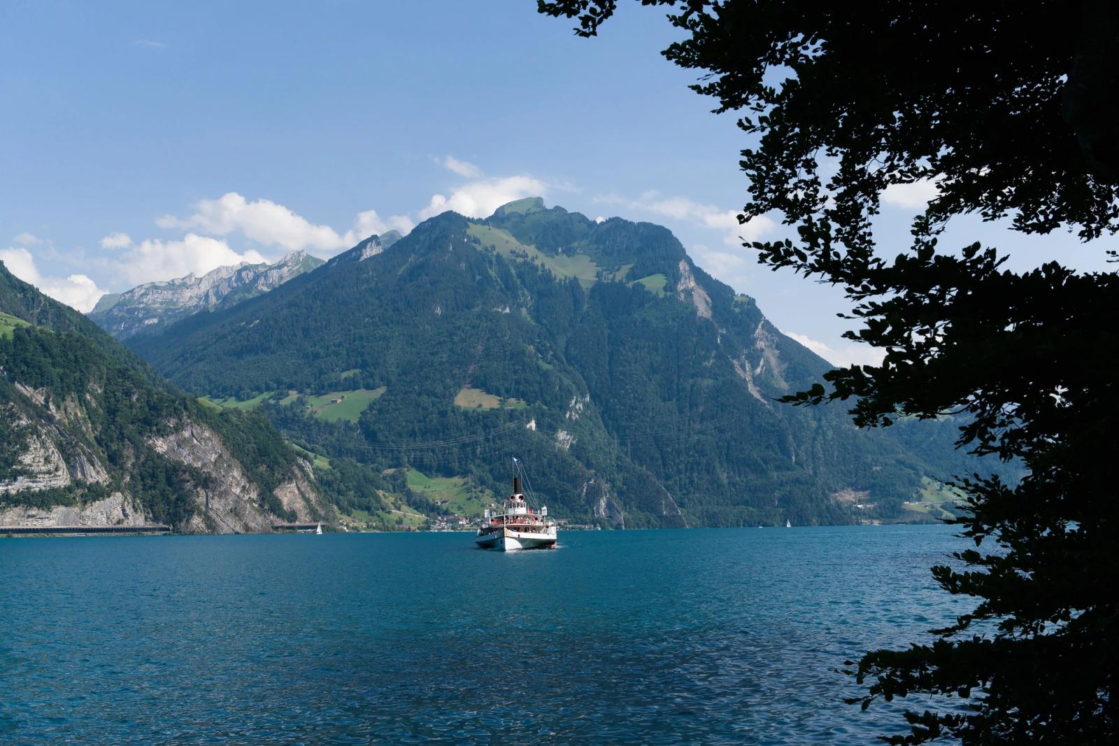 Boat sailing on Lake Lucerne with picturesque Swiss Alps backdrop under clear blue sky