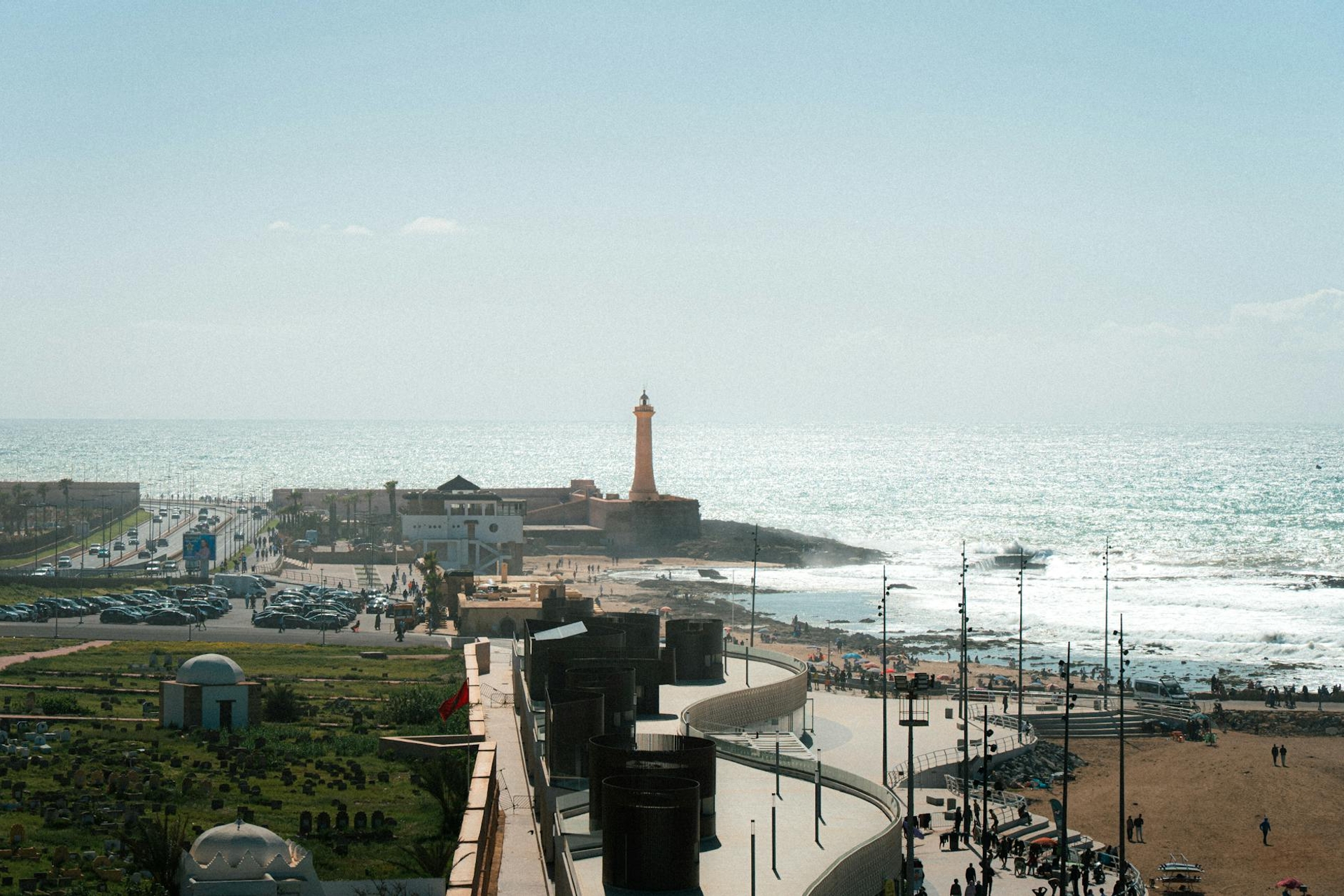 A coastal promenade with a tall lighthouse overlooking the ocean