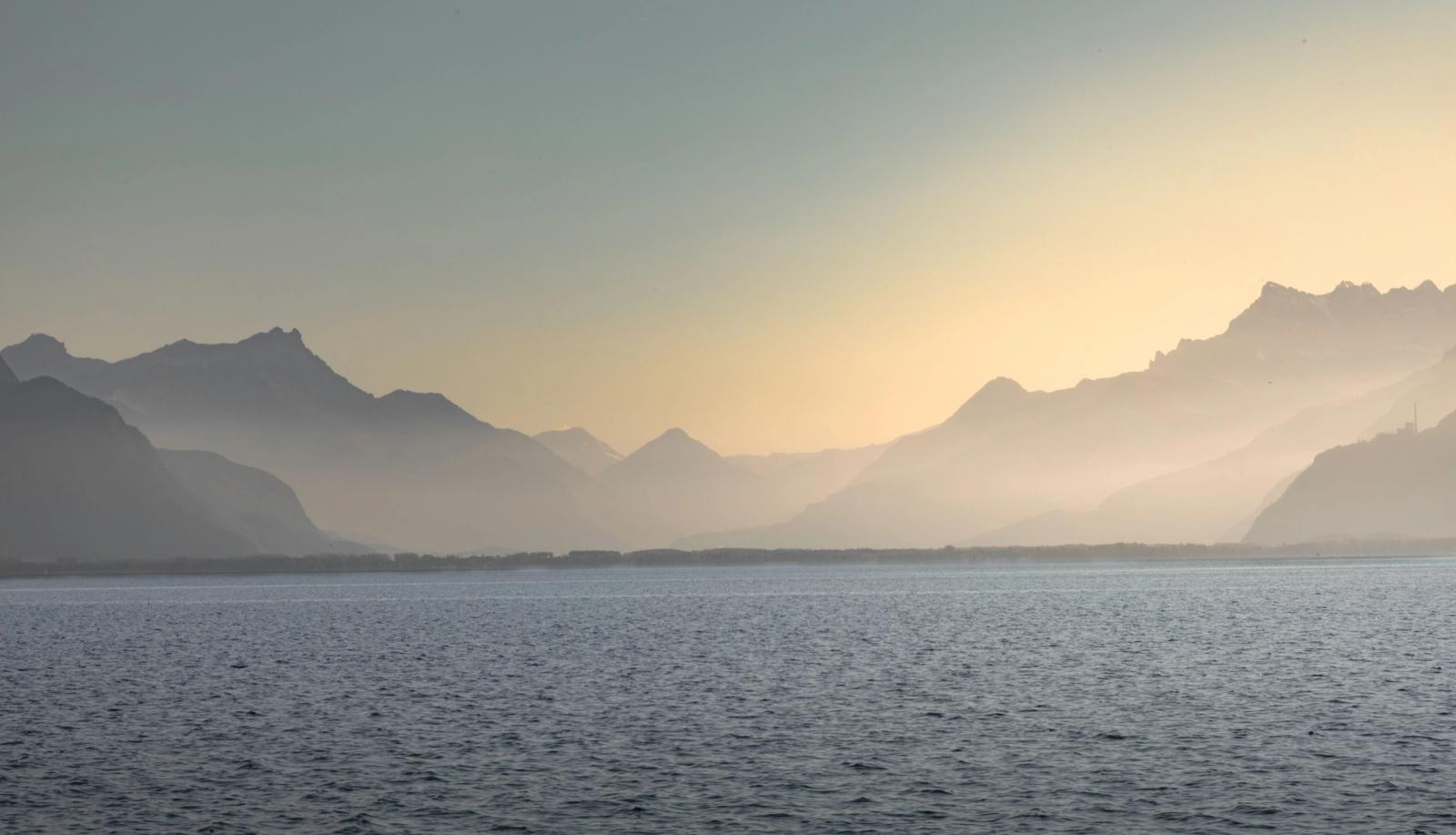 Peaceful view of misty mountains and Lake Geneva at sunset in Vevey, Switzerland