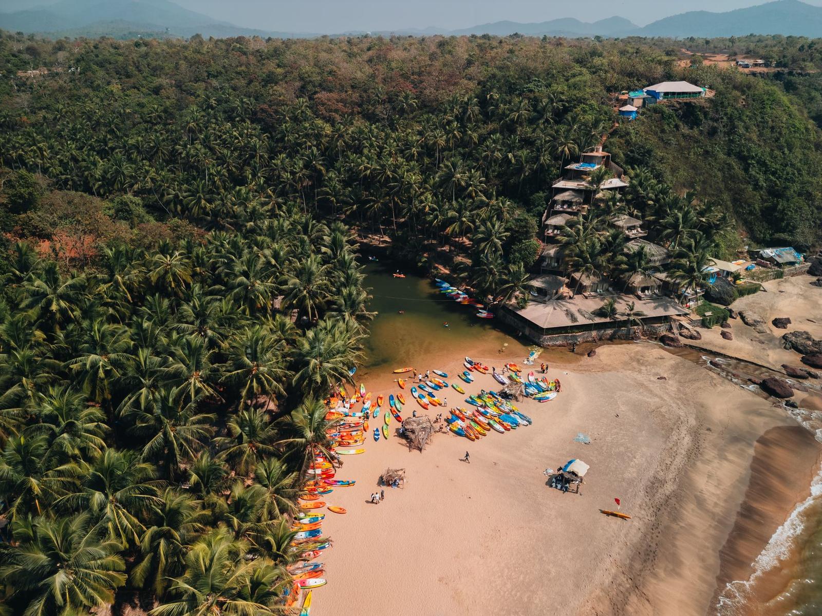 Aerial view of colourful kayaks lined on a palm-fringed beach cove