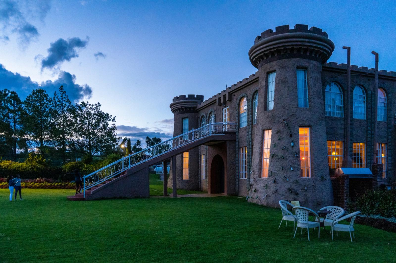 brown brick building with green grass lawn Beautiful evening on the green manicured lawns of Tafaria castle Kenya