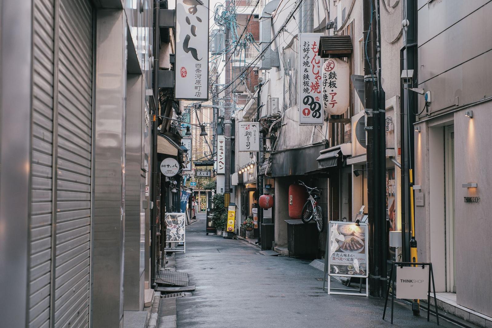 A narrow city alley lined with small shopfronts and hanging signs