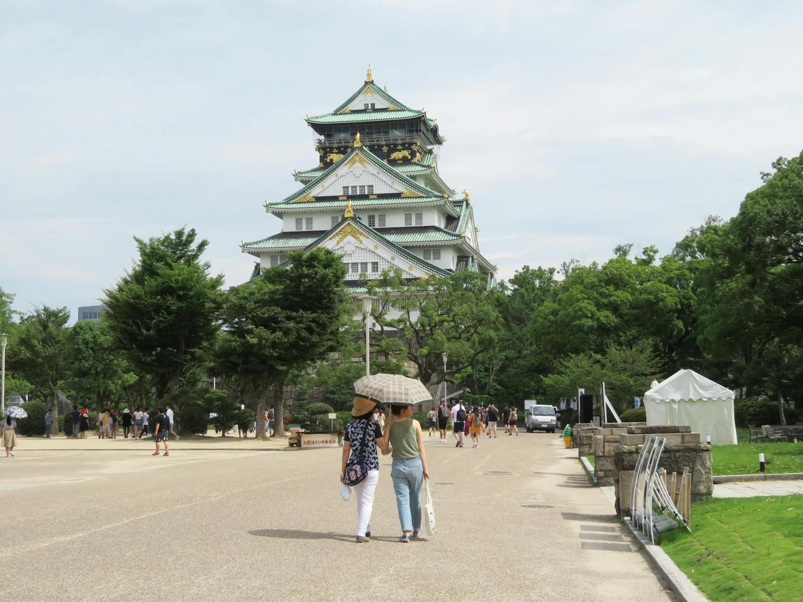 A multi-tiered castle tower with green roofs rising above a park
