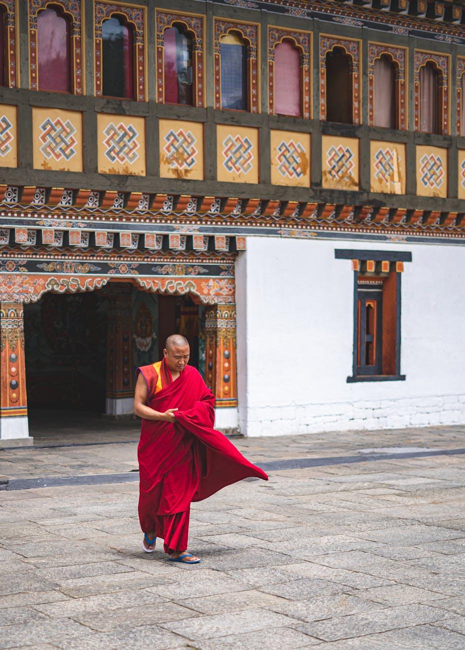 A monk in traditional attire walks through a beautifully decorated Bhutanese monastery
