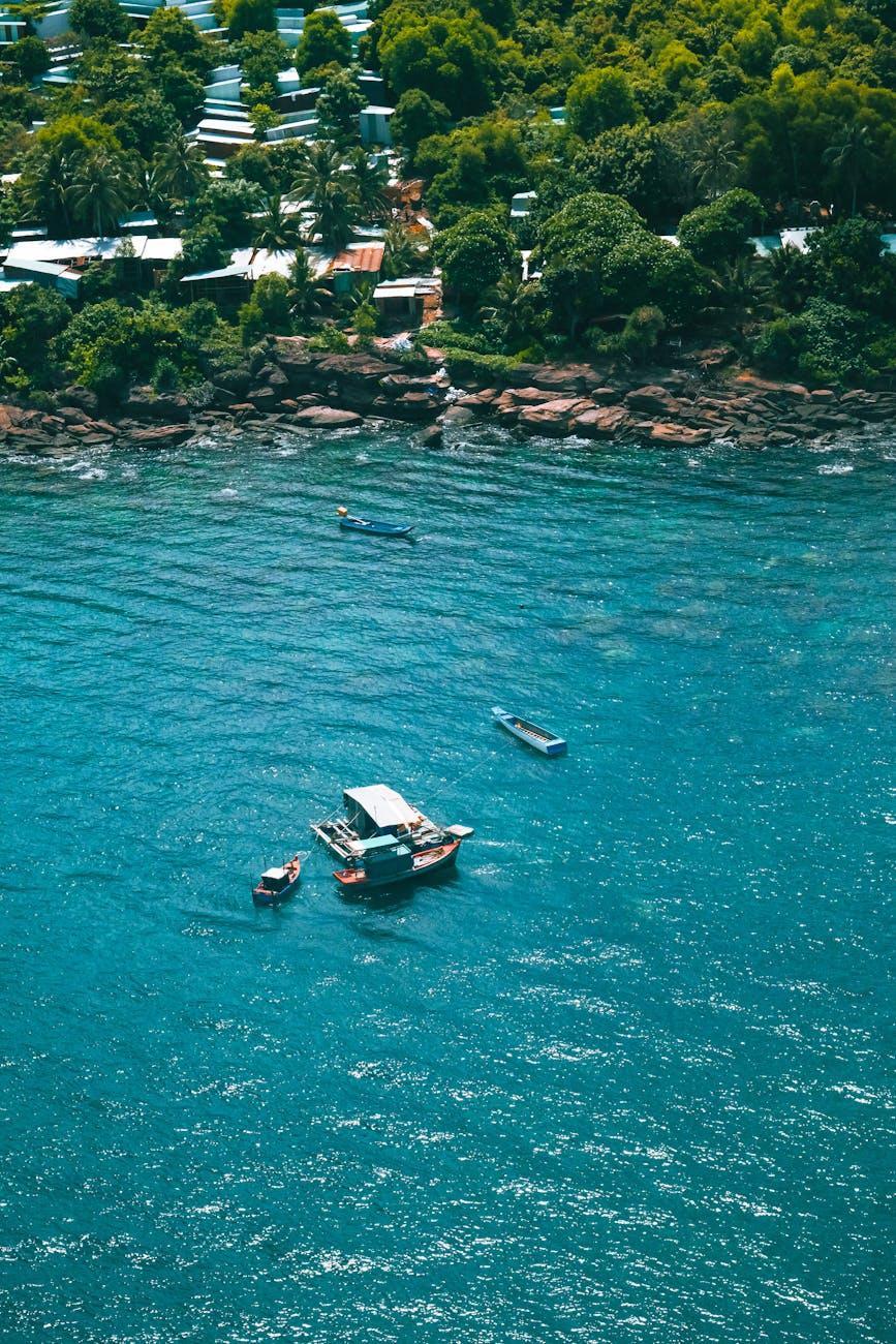 Small boats anchored in clear turquoise water off a rocky shore