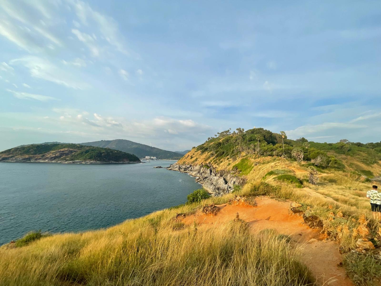 Explore the stunning coastal landscape of Promthep Cape, Phuket, with blue skies and rugged terrain