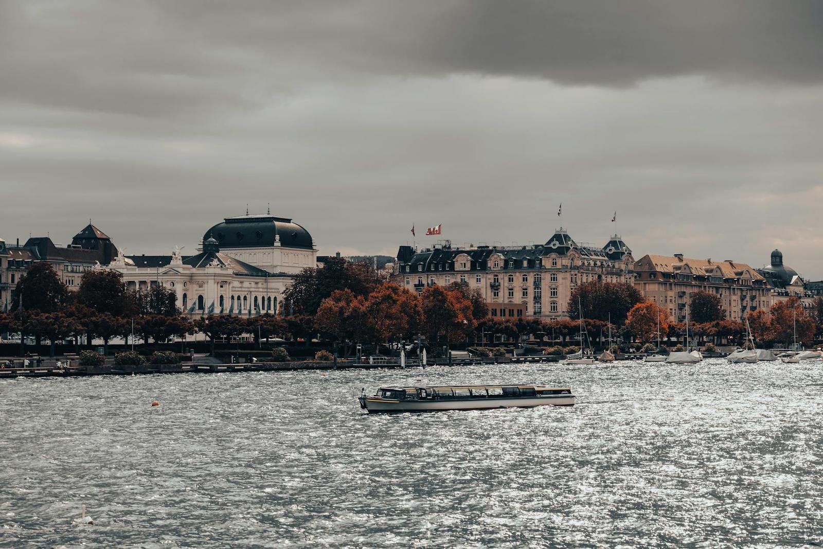 Ferry crossing choppy water past an ornate lakefront building under grey skies