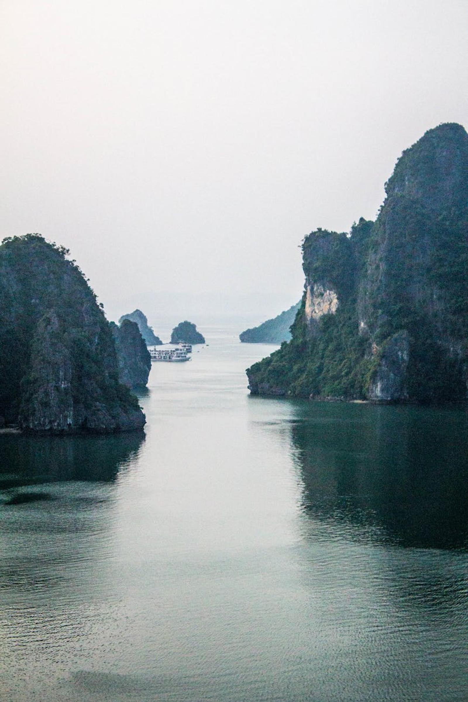 Serene landscape of karst formations in Halong Bay, Vietnam, with calm waters and overcast sky