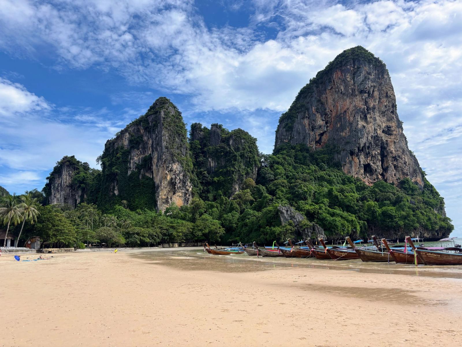 Scenic view of limestone cliffs and longtail boats at Railay Beach, Krabi, Thailand on a sunny day