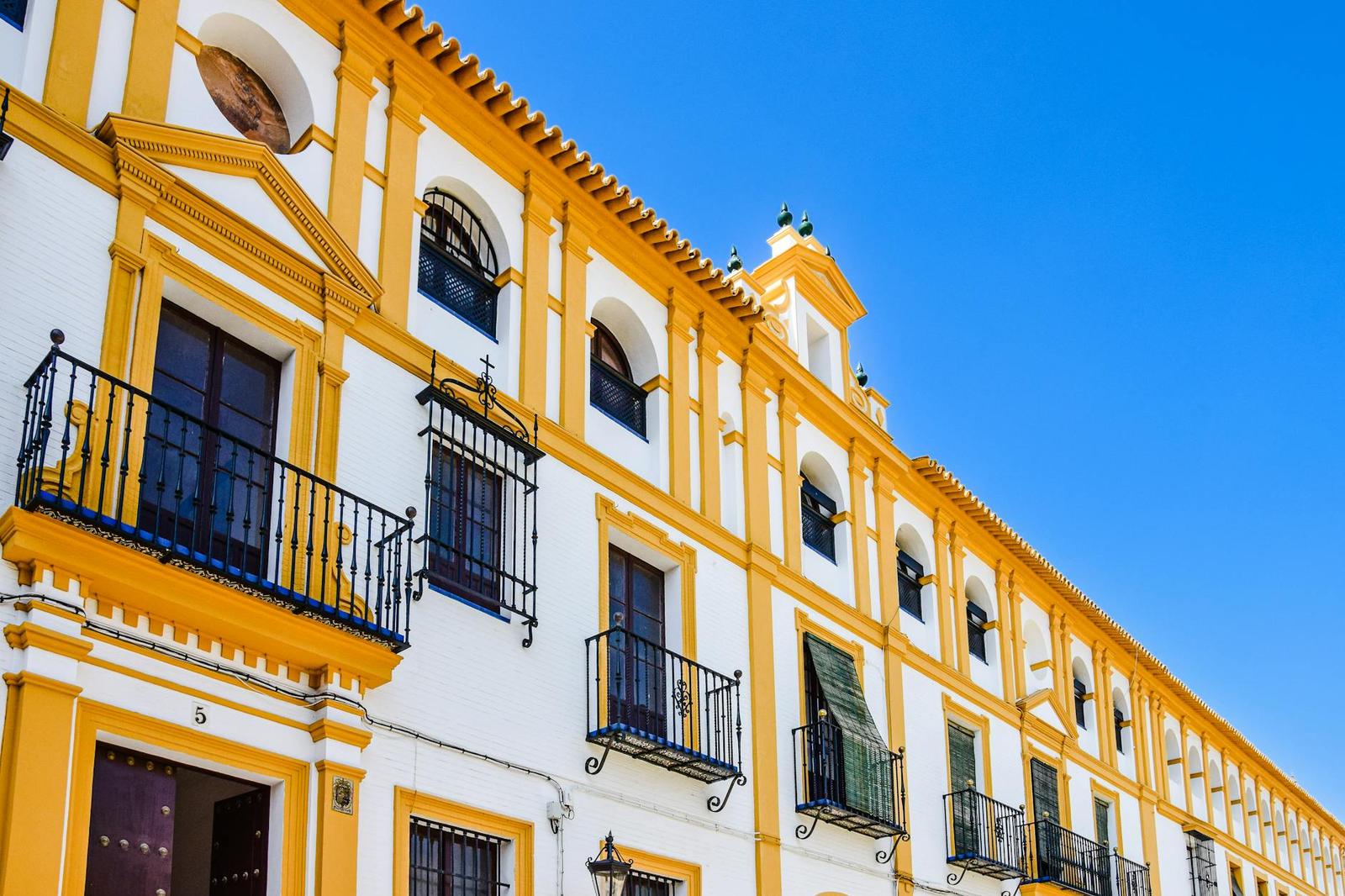 Yellow and white colonial facade with wrought-iron balconies against a clear sky