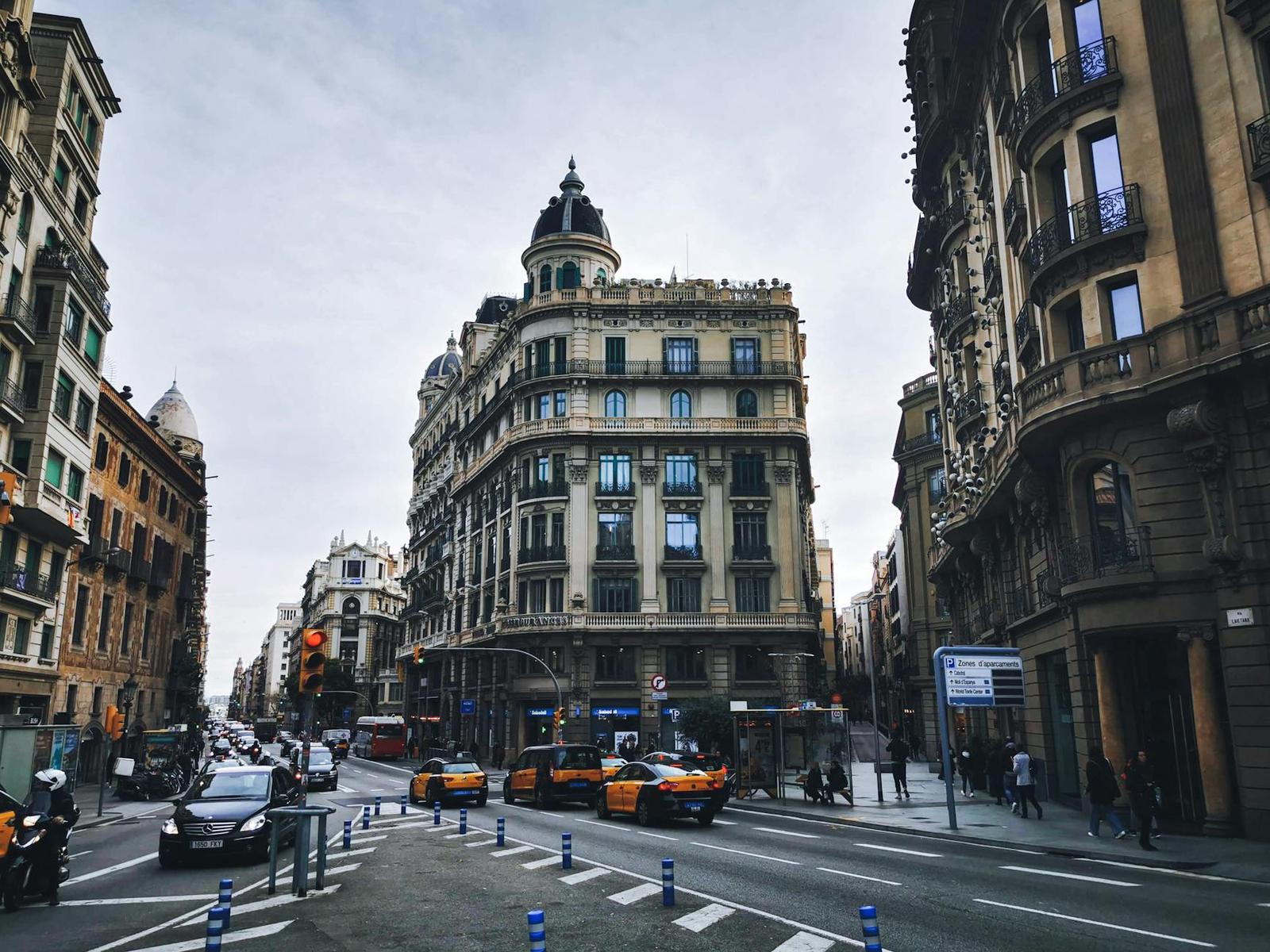 Ornate corner building at a busy city intersection with taxis and pedestrians