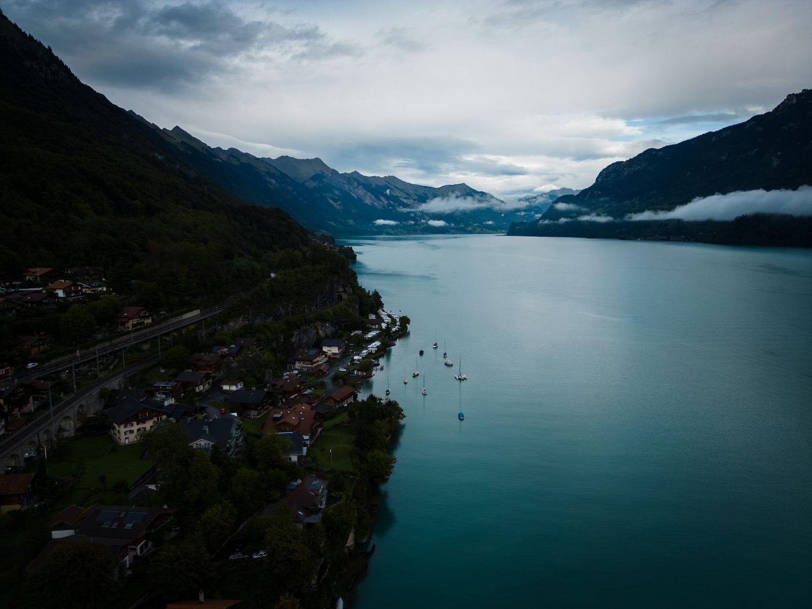 Aerial view of a lakeside village at dusk with boats moored offshore