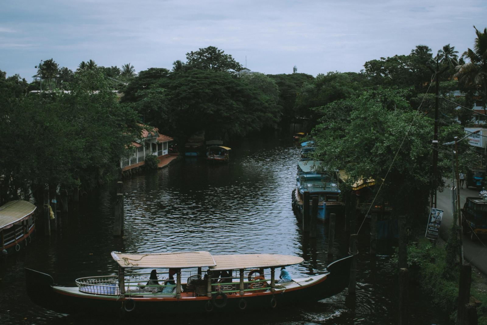 A serene river scene with boats in a lush Indian village, highlighting rural beauty