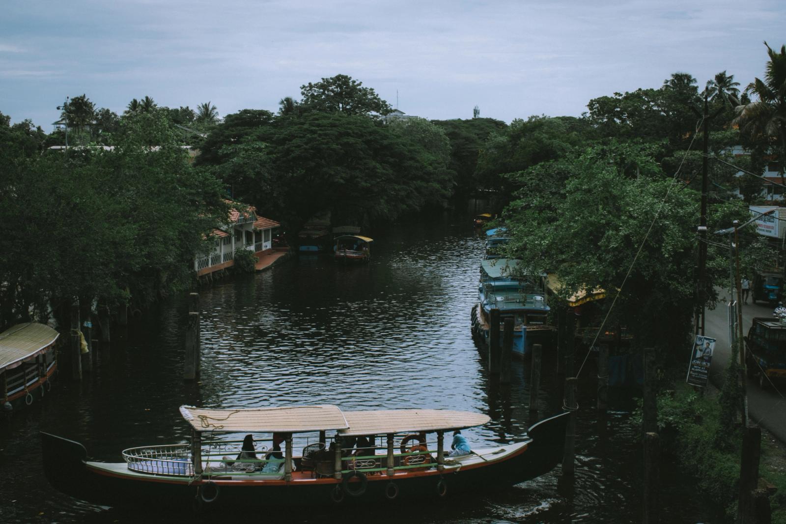 A serene river scene with boats in a lush Indian village, highlighting rural beauty
