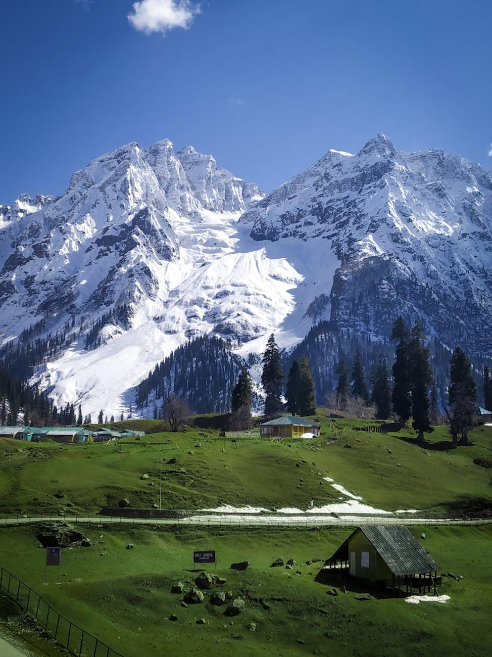 Stunning view of snow-covered mountains and vibrant green grassland in Kashmir