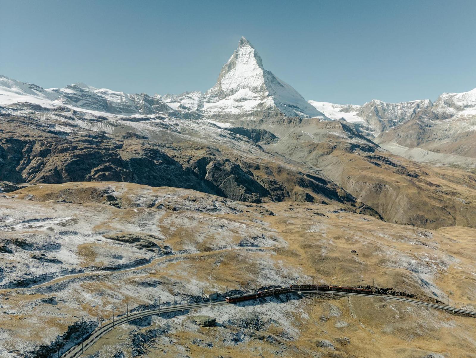 Pyramid-shaped snow-capped peak above a mountain railway line