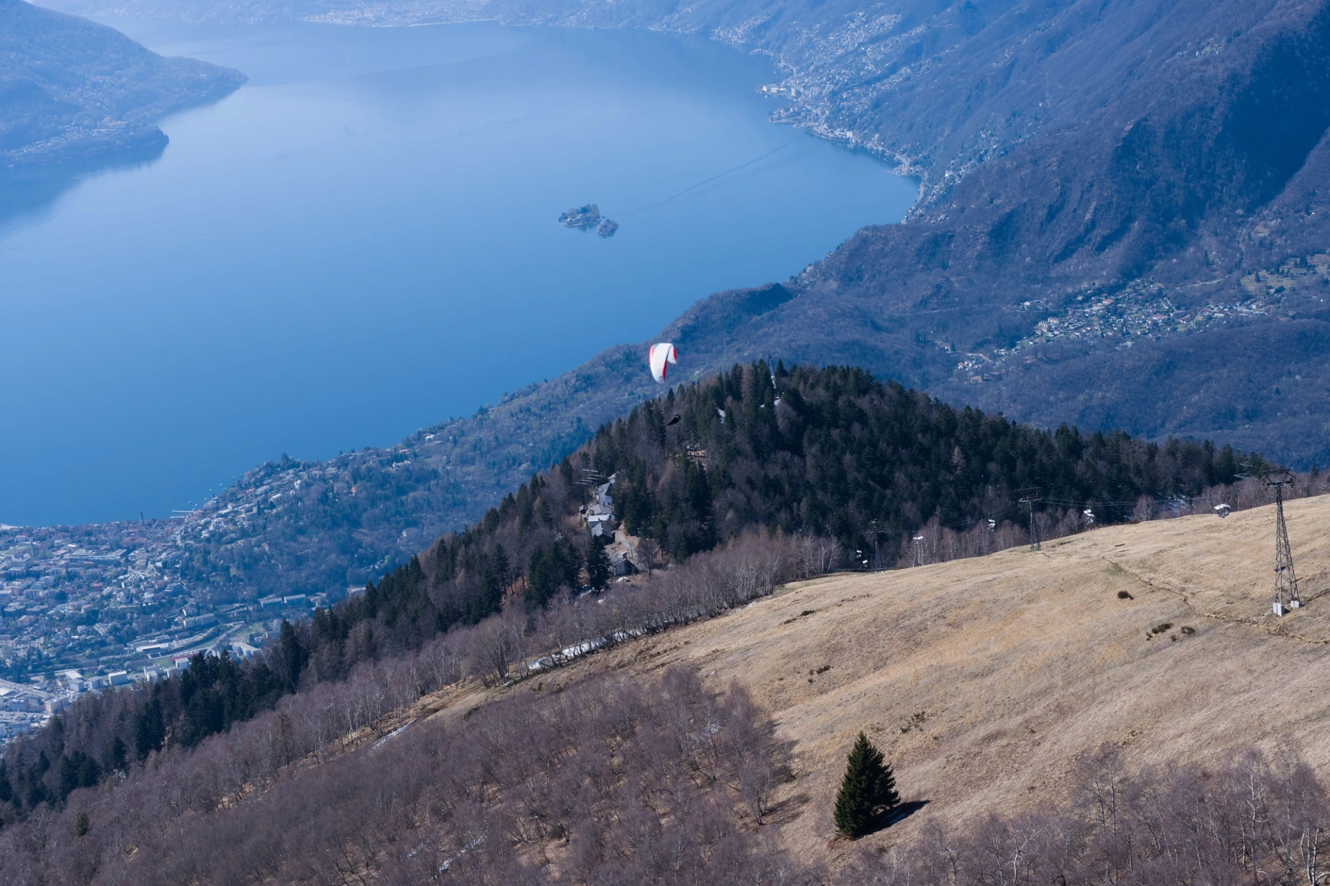 Aerial view of a paraglider over Swiss Alps, showcasing Lake Maggiore