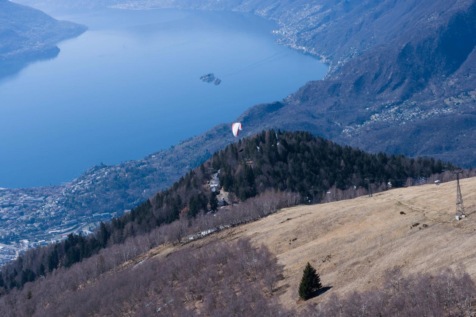 Aerial view of a paraglider over Swiss Alps, showcasing Lake Maggiore