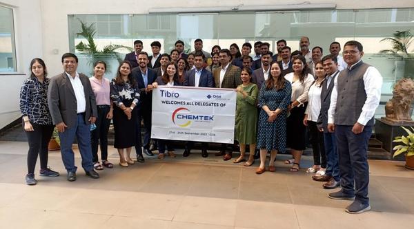 A large group posing with a banner at a Chemtek event.