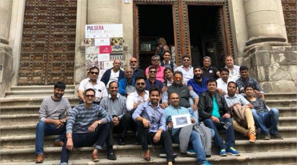 Group posing on historic stone steps with ornate wooden doors.