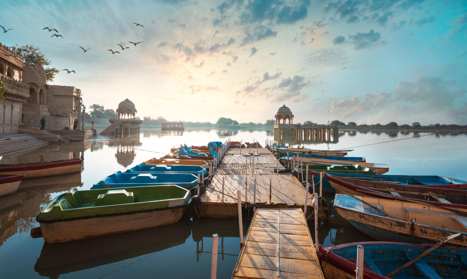 Rowboats moored at a stepped lakeside ghat with domed pavilions