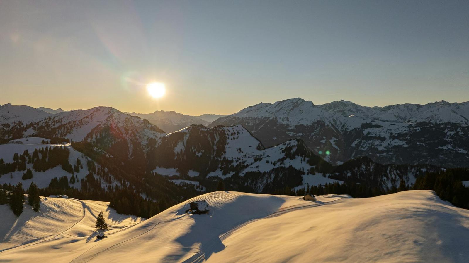 Sunburst over snow-covered mountain ridges at dawn