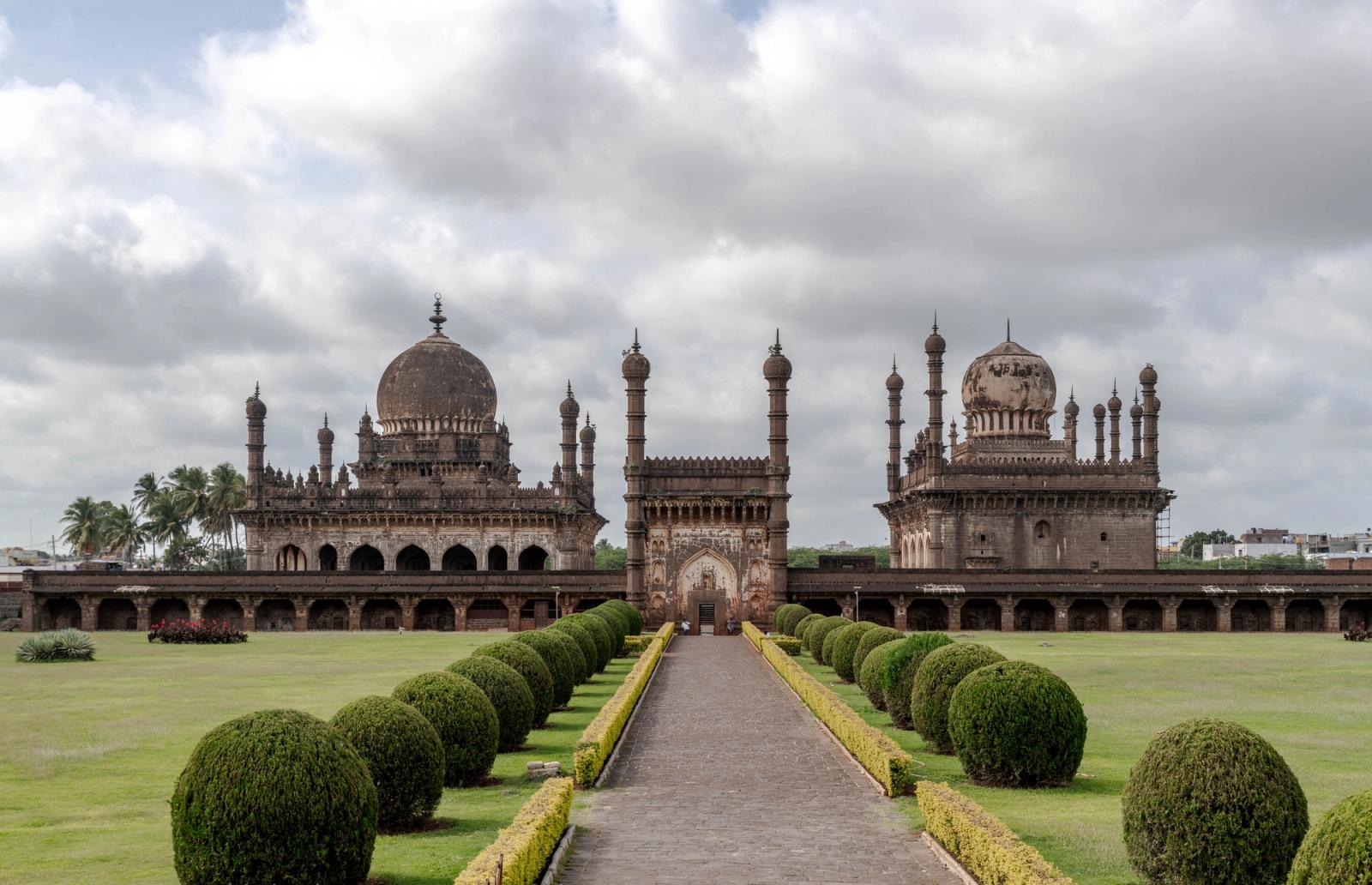 A domed mausoleum complex framed by a manicured garden pathway
