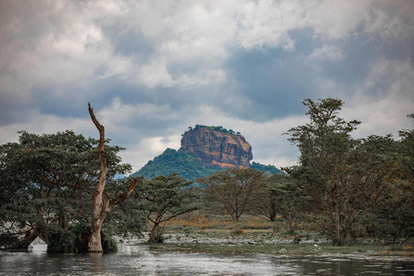 Majestic Sigiriya Rock amidst lush foliage and moody clouds in Sri Lanka
