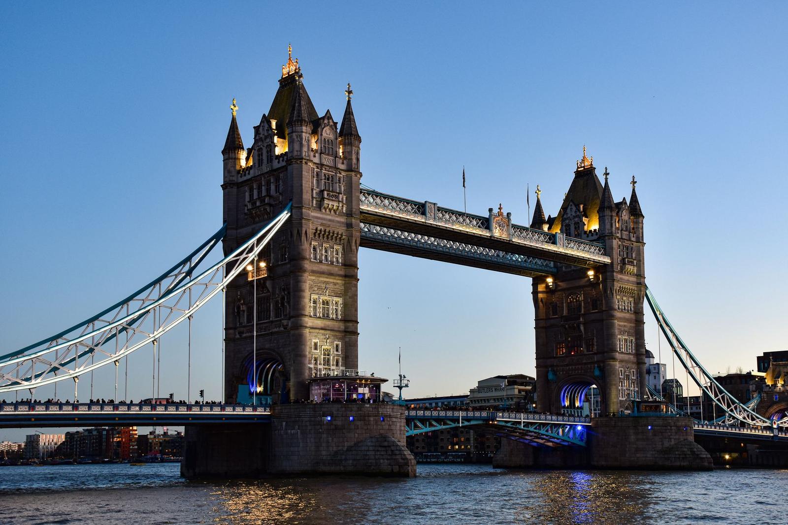 A twin-towered suspension bridge over a river at dusk