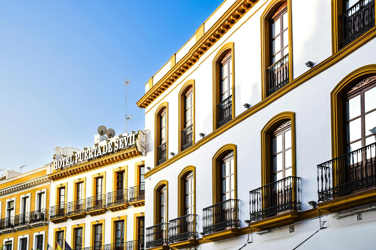 Ornate white and ochre hotel facade with wrought-iron balconies and arched windows