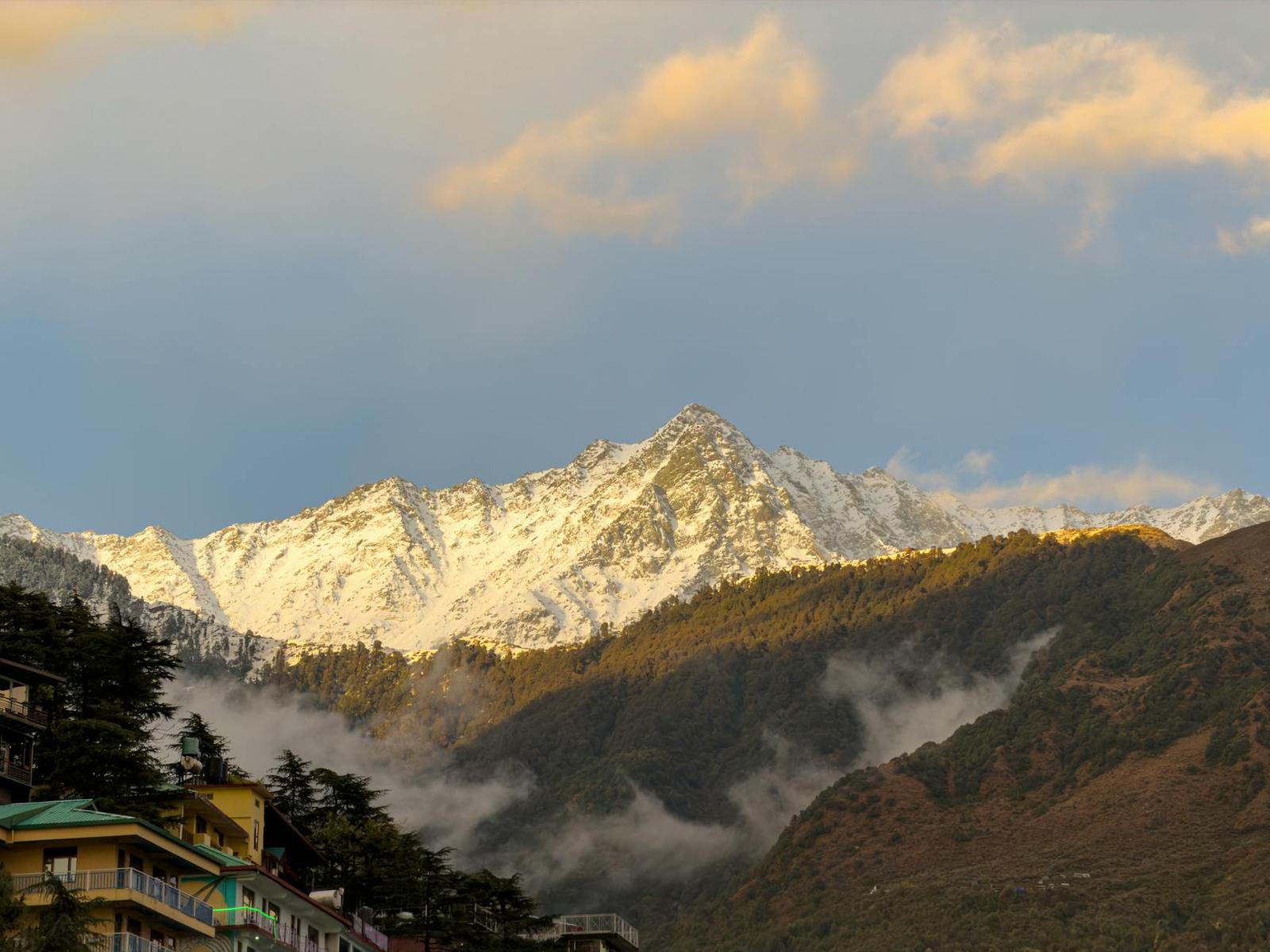 Snow-capped peaks rising above a misty forested ridge